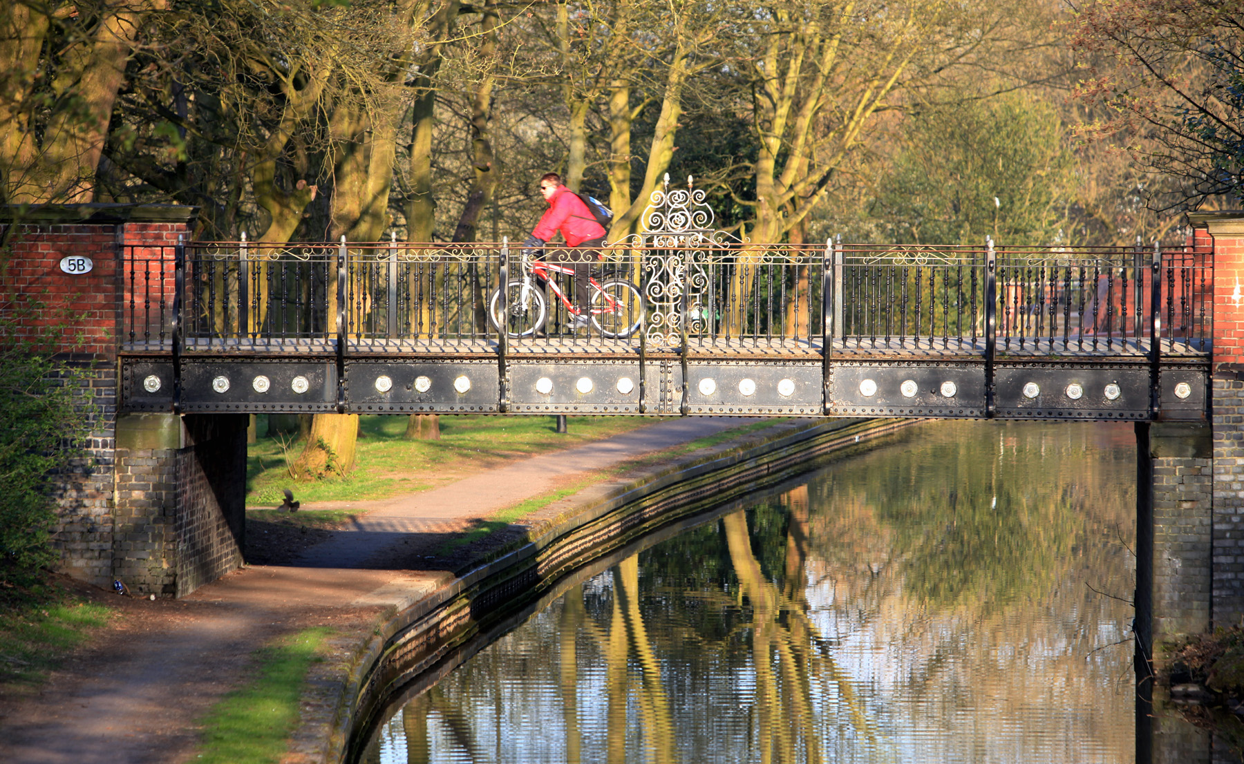 Man riding bike over a bridge in Hanley Park