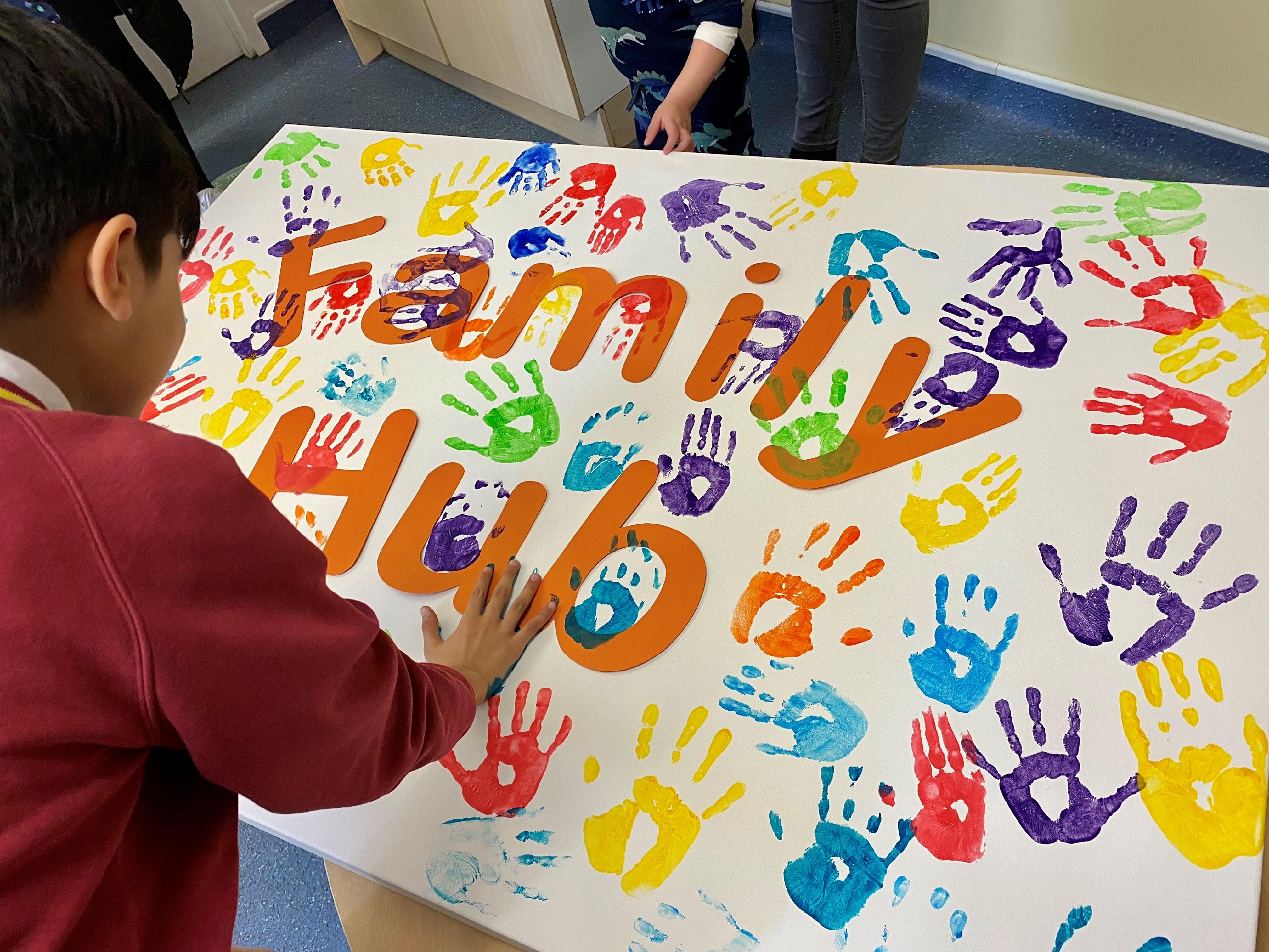 Child painting with handprints on a family hub poster